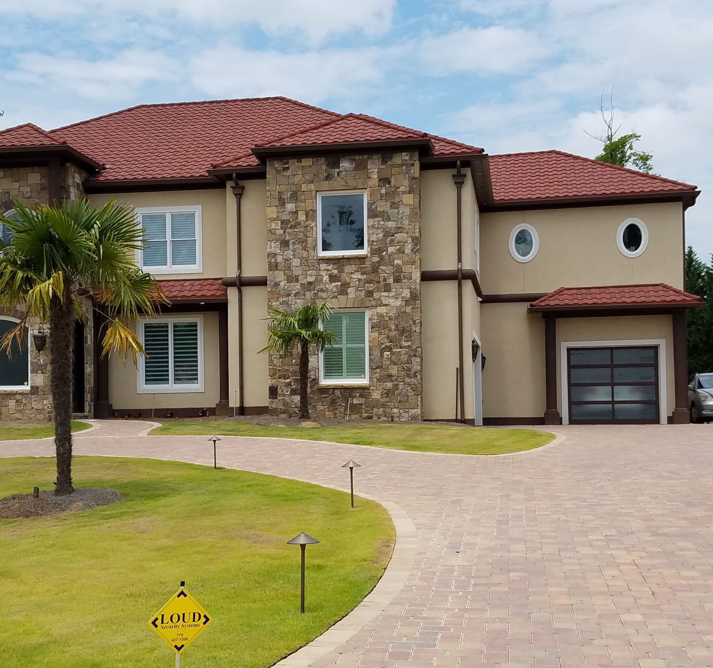 Red stone-coated steel barrel tile roof on a two-story stucco and stone home