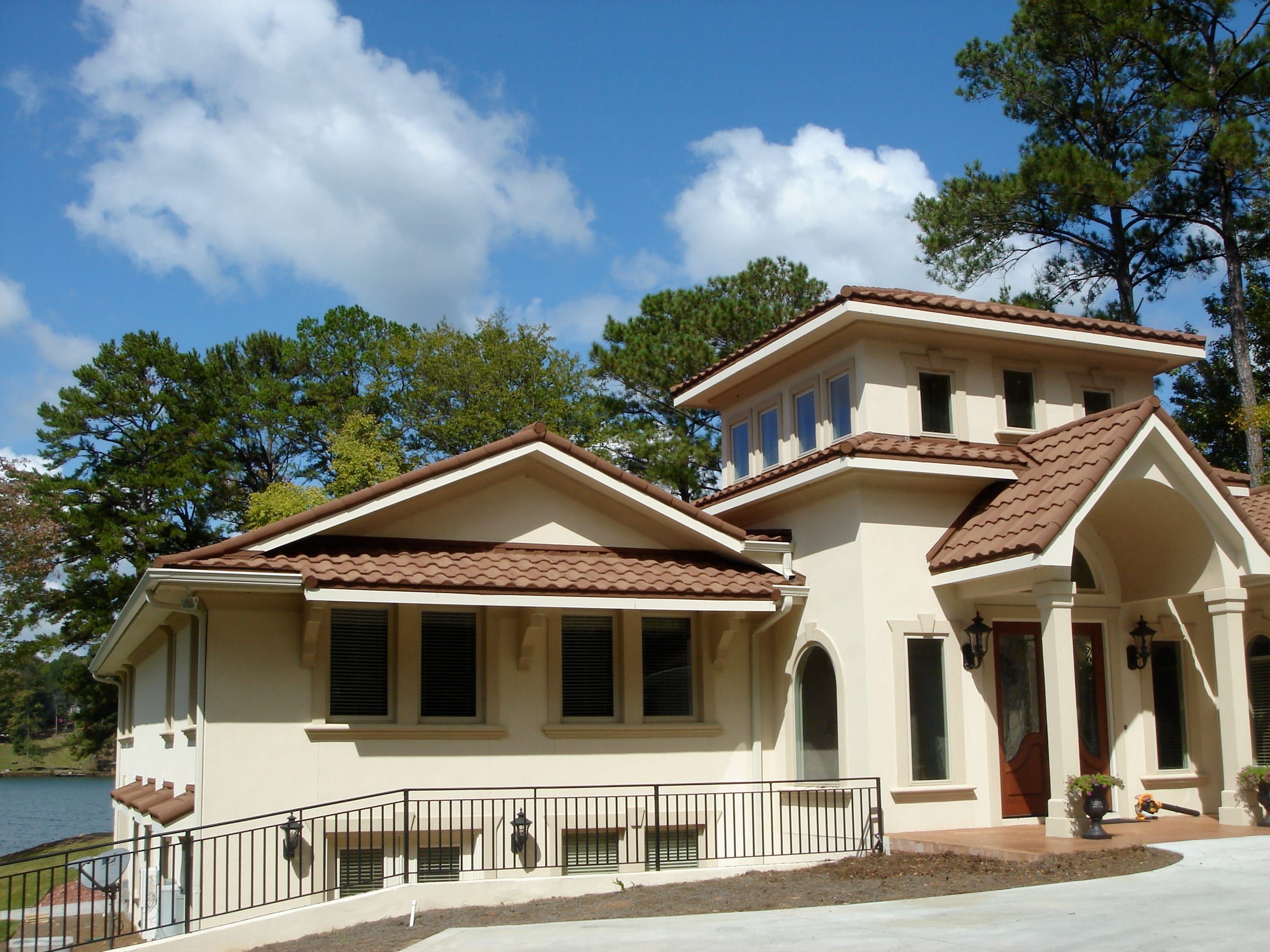 Terracotta-colored stone-coated steel Tuscan tile roof on a stucco lake house